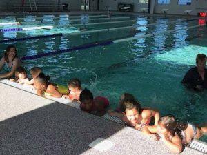 kids lined up on wall of pool